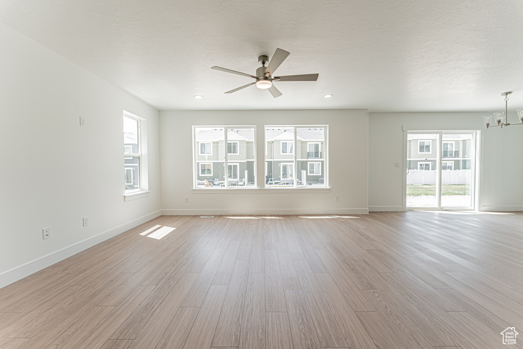 Empty room featuring a chandelier, a ceiling fan, light wood-type flooring, and recessed lighting