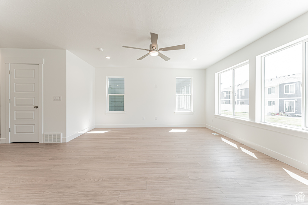 Empty room with a ceiling fan, light wood-type flooring, and recessed lighting
