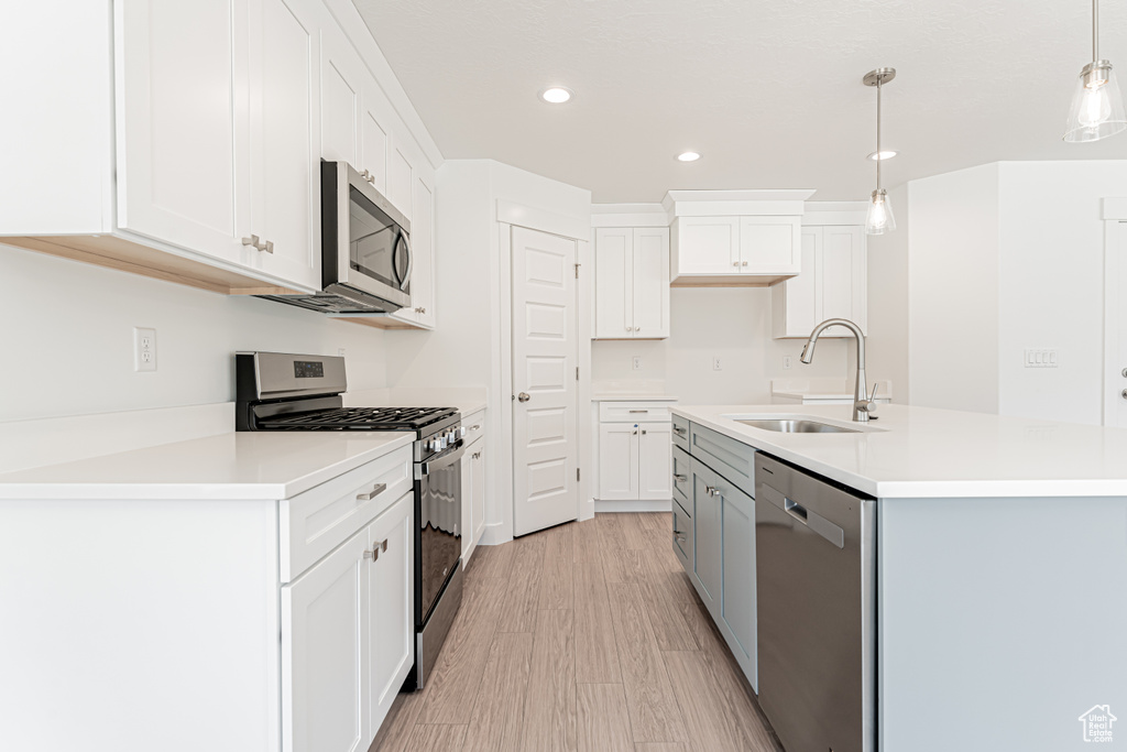 Kitchen featuring stainless steel appliances, recessed lighting, white cabinetry, pendant lighting, and light countertops