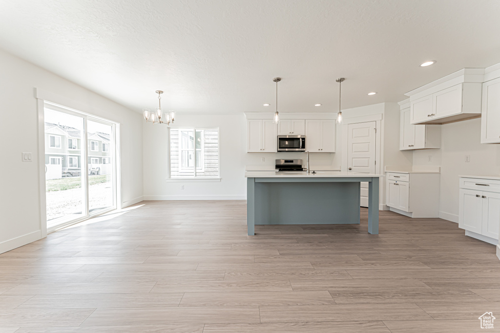 Kitchen with appliances with stainless steel finishes, a chandelier, recessed lighting, white cabinetry, and light wood-style floors