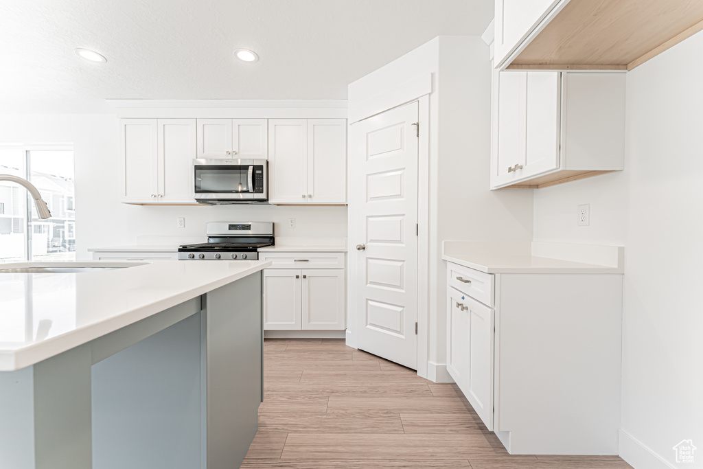Kitchen featuring appliances with stainless steel finishes, recessed lighting, light countertops, white cabinets, and light wood-type flooring