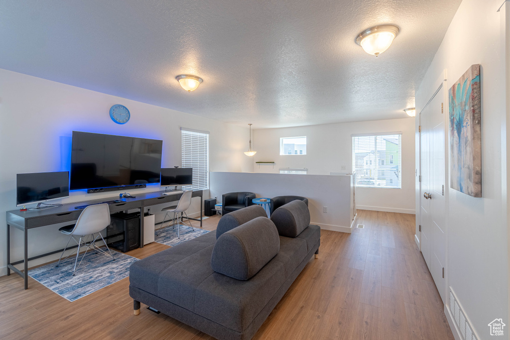 Living area with visible vents, baseboards, light wood-type flooring, and a textured ceiling