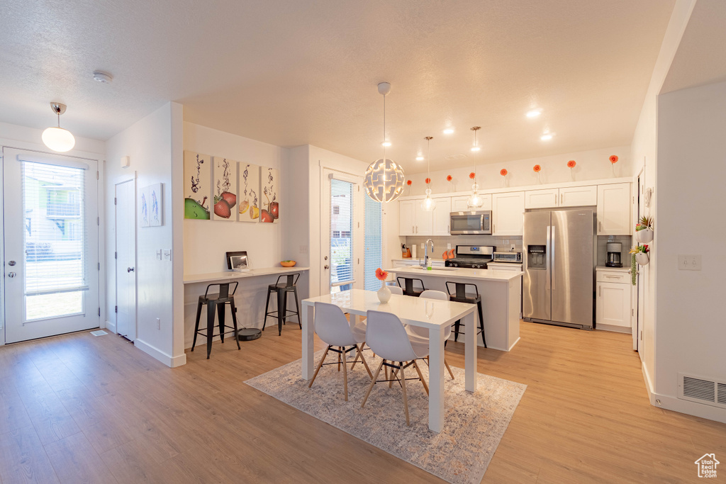 Dining room featuring baseboards, light wood-type flooring, a notable chandelier, and visible vents