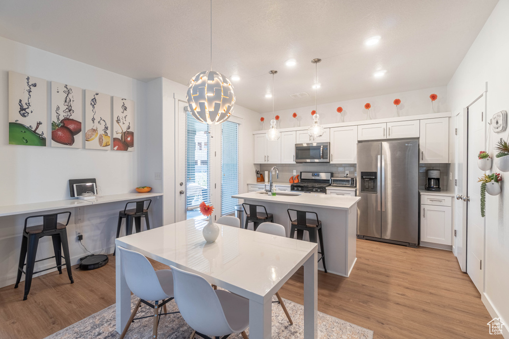 Dining space featuring light wood finished floors, a notable chandelier, and recessed lighting
