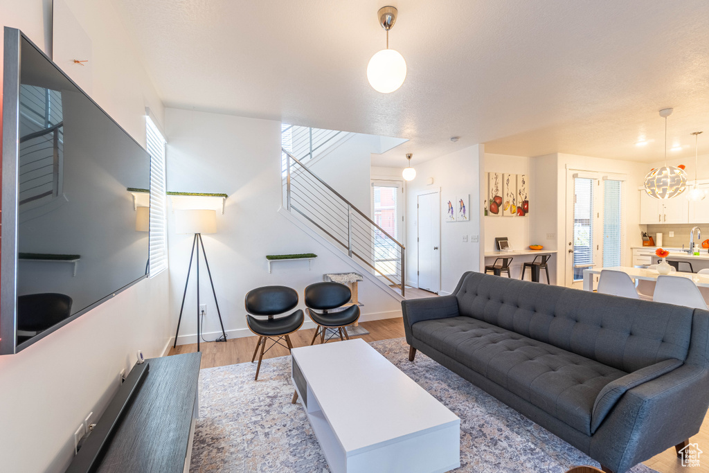 Living room with wood finished floors, a healthy amount of sunlight, baseboards, and stairway