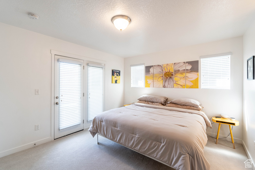 Carpeted bedroom featuring baseboards, access to exterior, and a textured ceiling