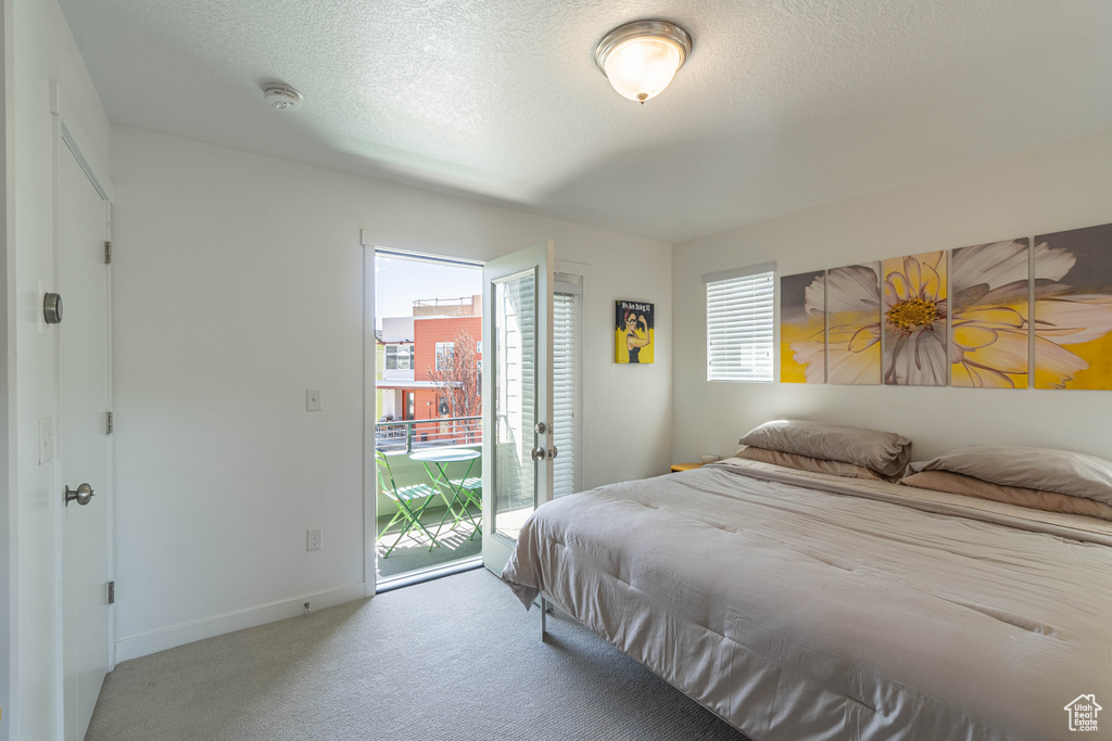 Carpeted bedroom featuring access to outside, baseboards, and a textured ceiling
