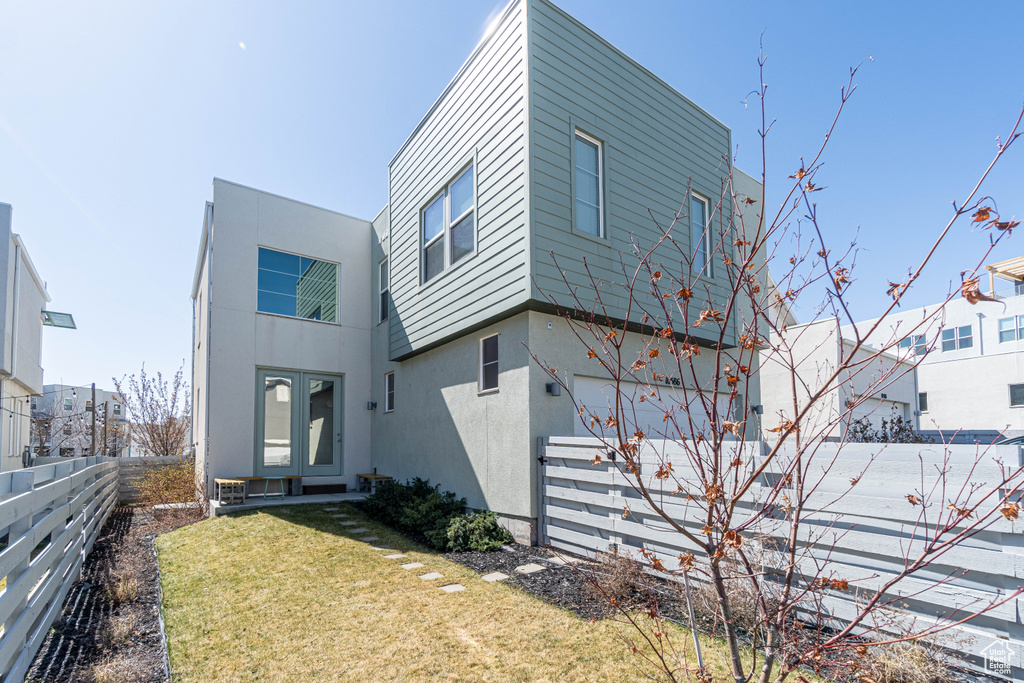Exterior space with french doors, stucco siding, fence, and a front lawn