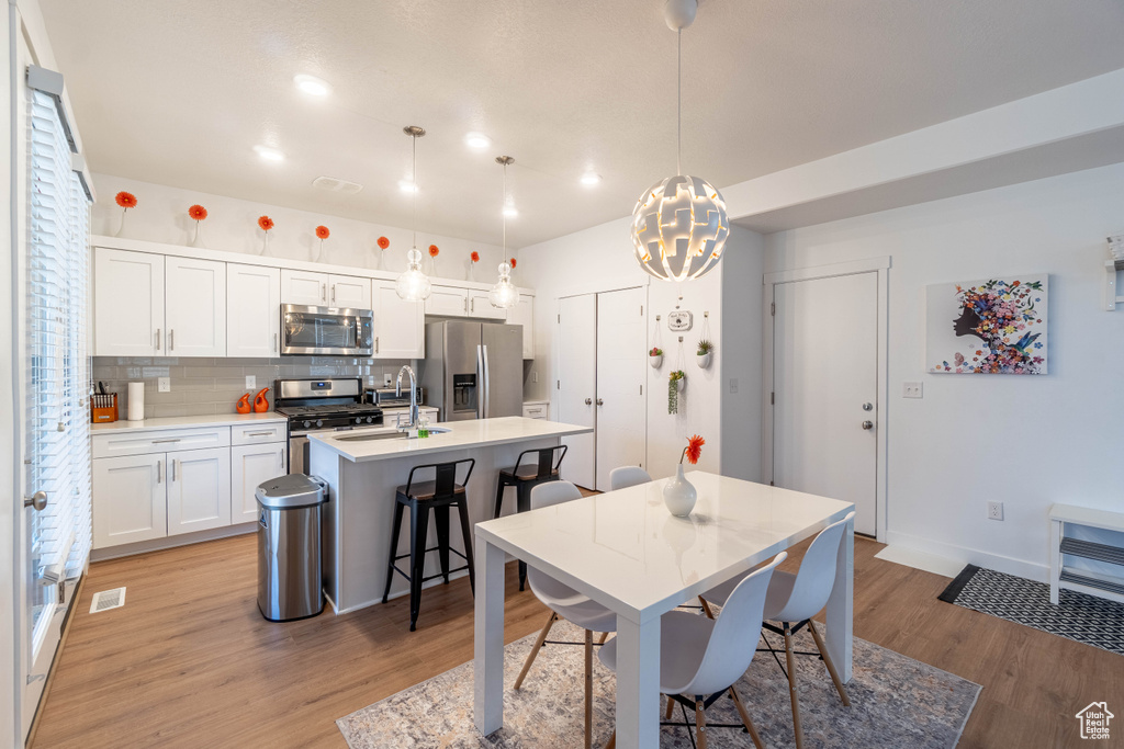 Dining room with visible vents, baseboards, a notable chandelier, and light wood-style floors