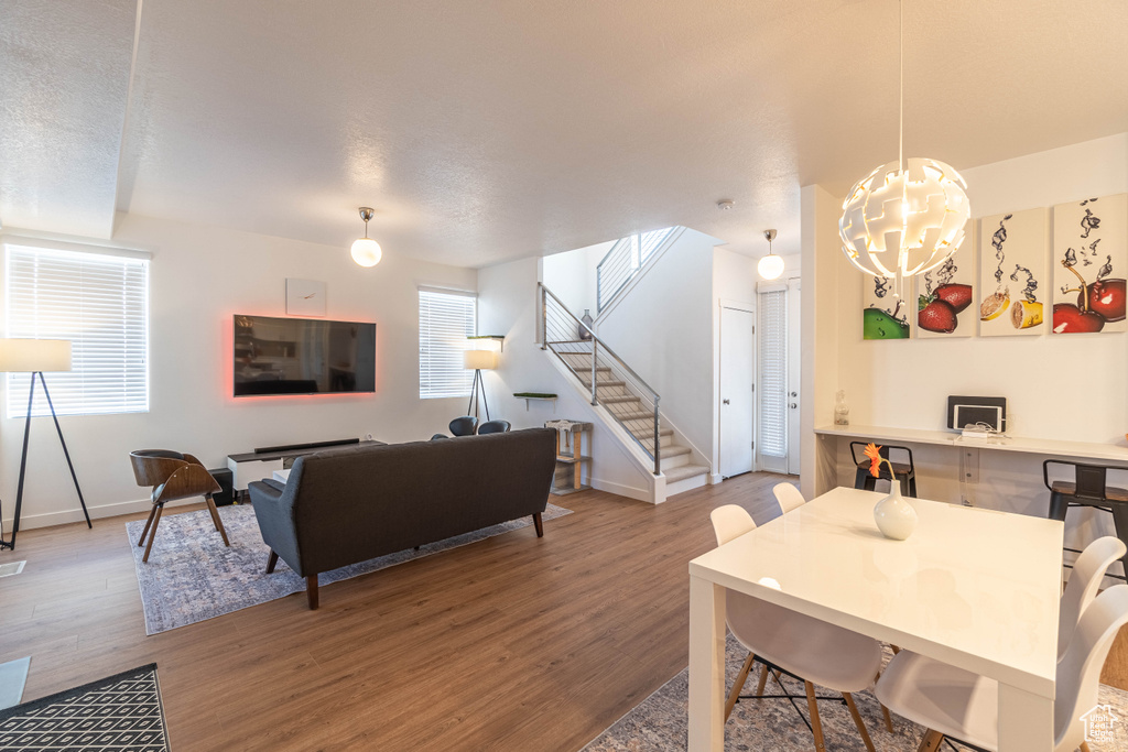 Dining room with wood finished floors, a notable chandelier, baseboards, and stairway