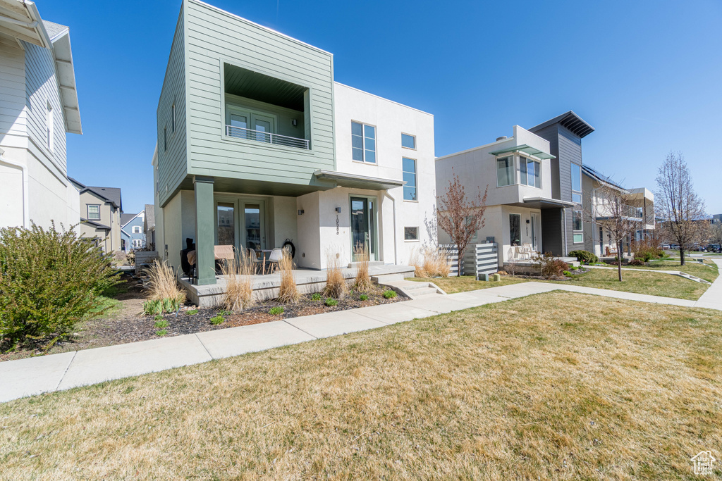 View of front of home featuring a patio area, stucco siding, a front lawn, and a balcony