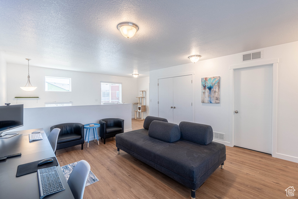 Living area with visible vents, light wood finished floors, and a textured ceiling