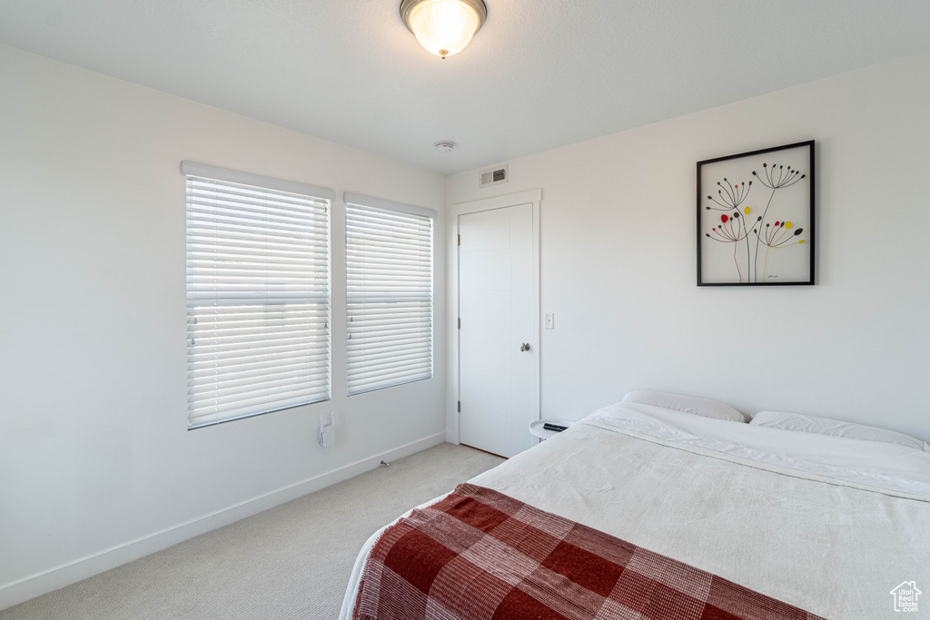Bedroom with light carpet, visible vents, and baseboards