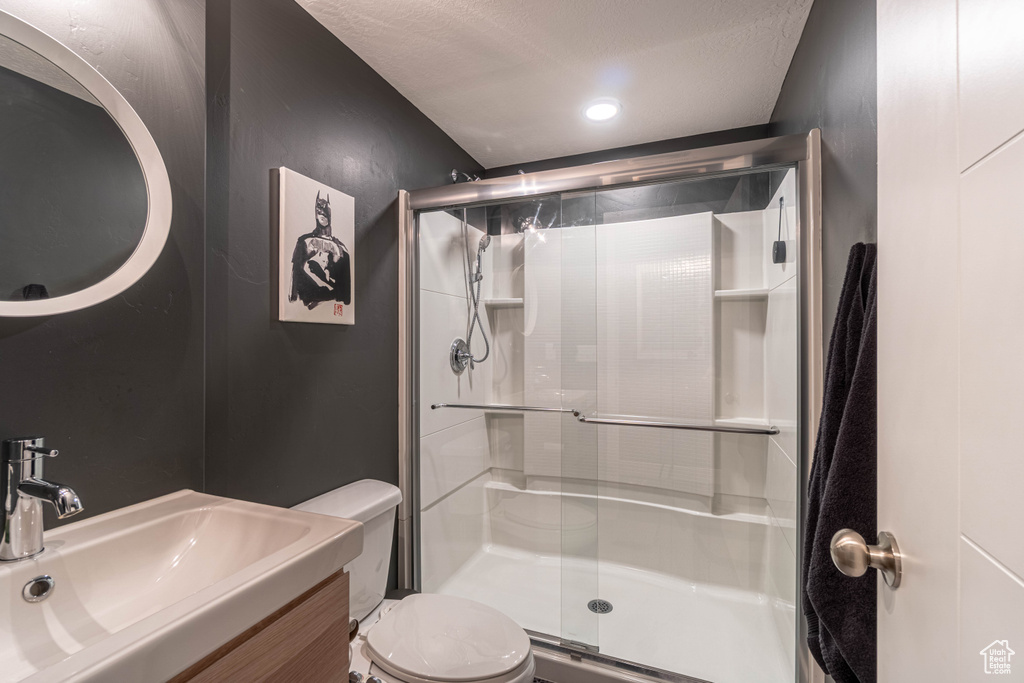 Full bath featuring a shower stall, vanity, a textured ceiling, and toilet