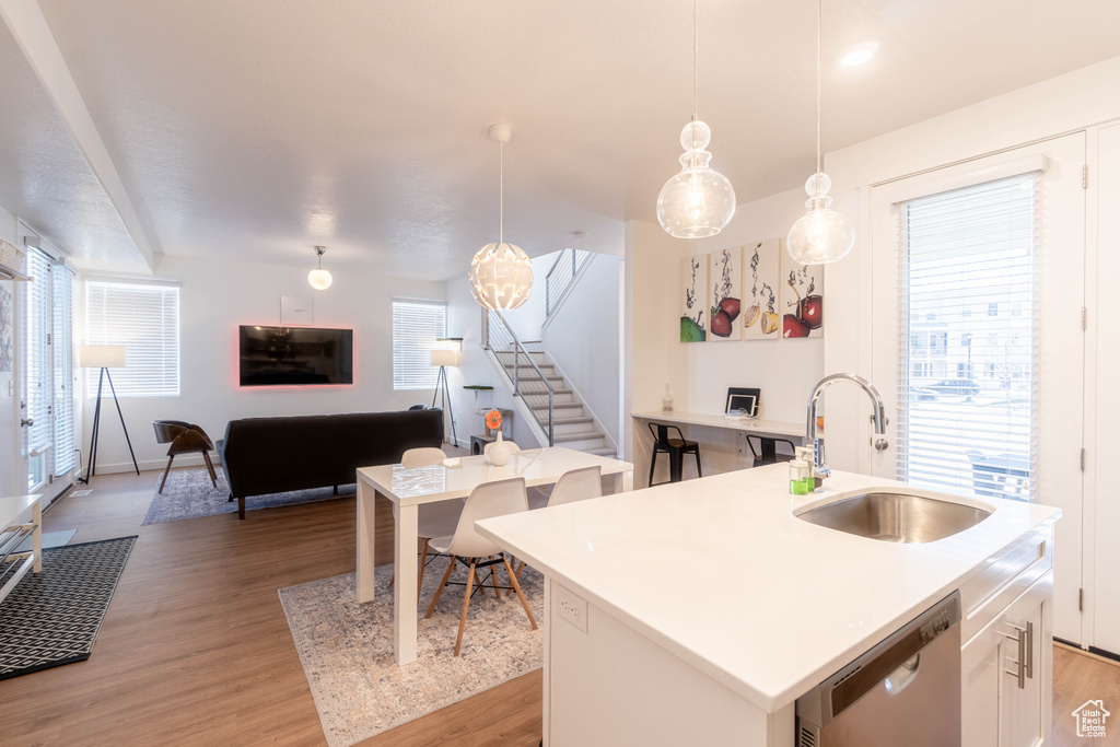 Kitchen featuring stainless steel dishwasher, light wood finished floors, and a sink