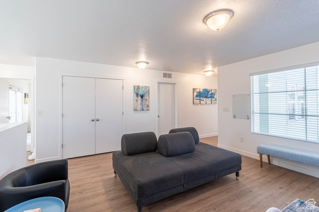 Living area featuring a textured ceiling, light wood finished floors, baseboards, and visible vents