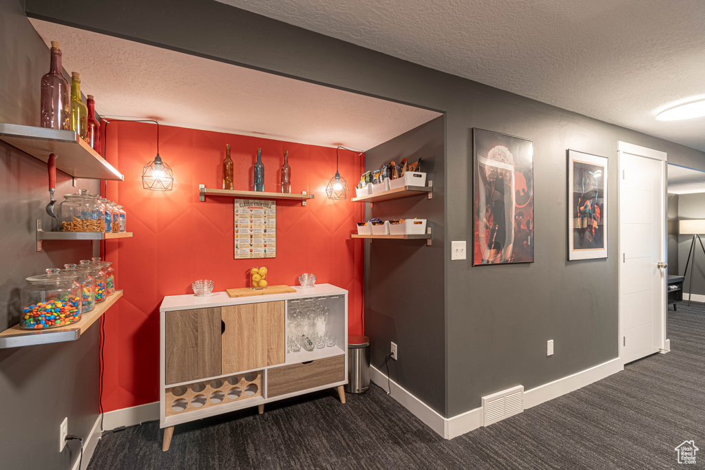 Bar with baseboards, carpet flooring, a textured ceiling, and visible vents