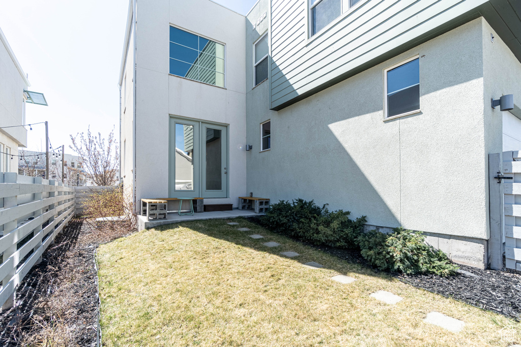 Exterior space with stucco siding, fence, and a lawn
