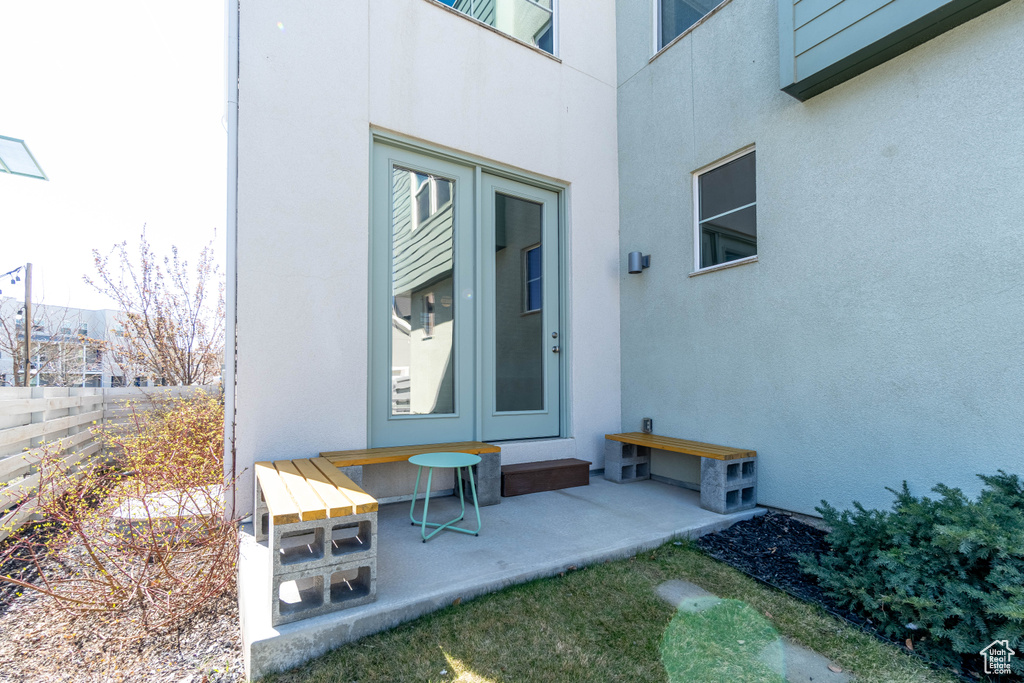 Doorway to property featuring a patio, stucco siding, and fence