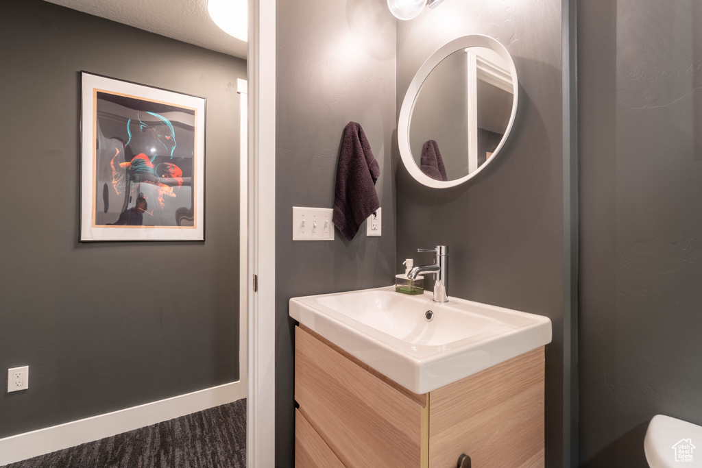 Bathroom featuring toilet, vanity, and baseboards
