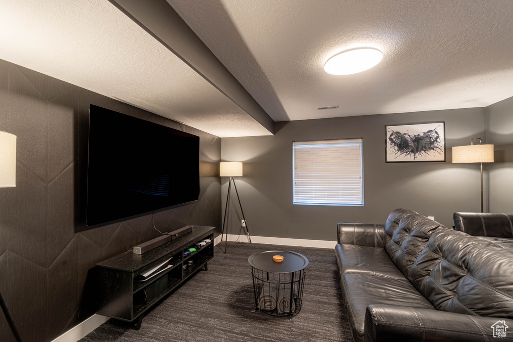 Living room with visible vents, baseboards, dark carpet, and a textured ceiling