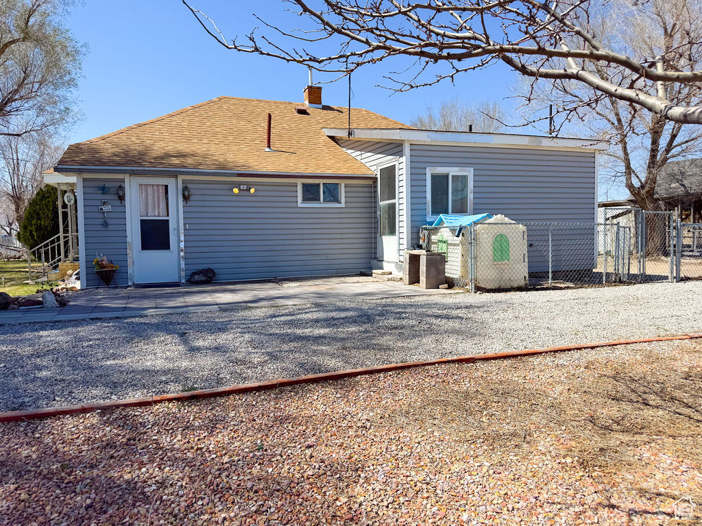 Back of property with roof with shingles, fence, driveway, and a chimney