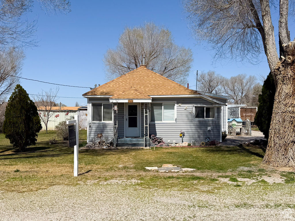 Bungalow-style house with a front lawn, fence, and a shingled roof