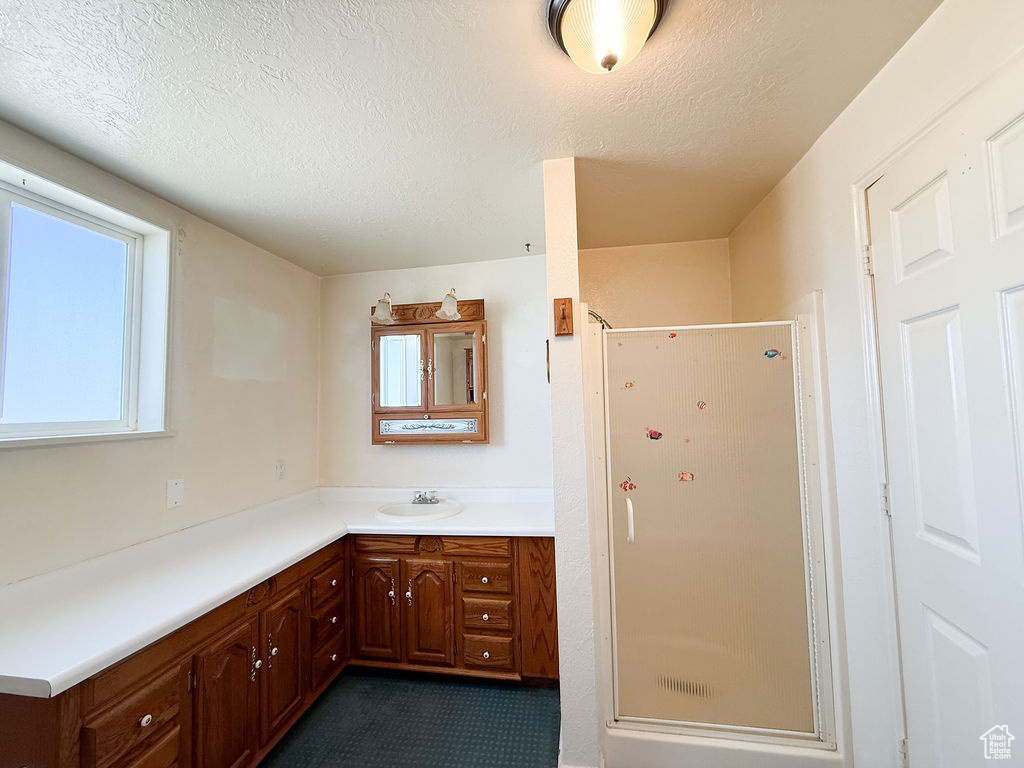 Bathroom featuring a shower stall, a textured ceiling, vanity, and plenty of natural light