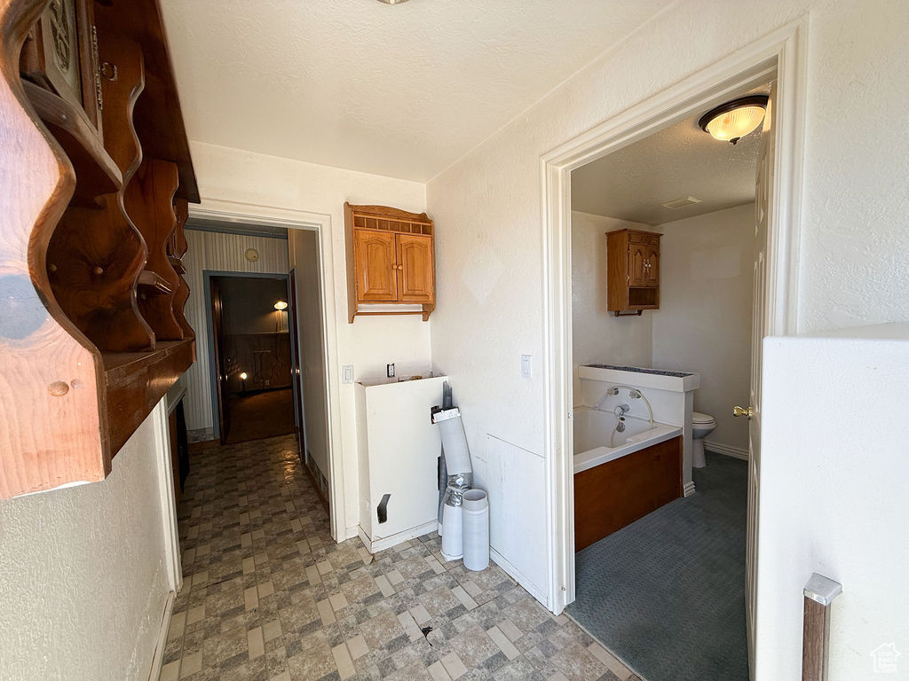 Interior space featuring toilet, a textured ceiling, baseboards, and tile patterned floors
