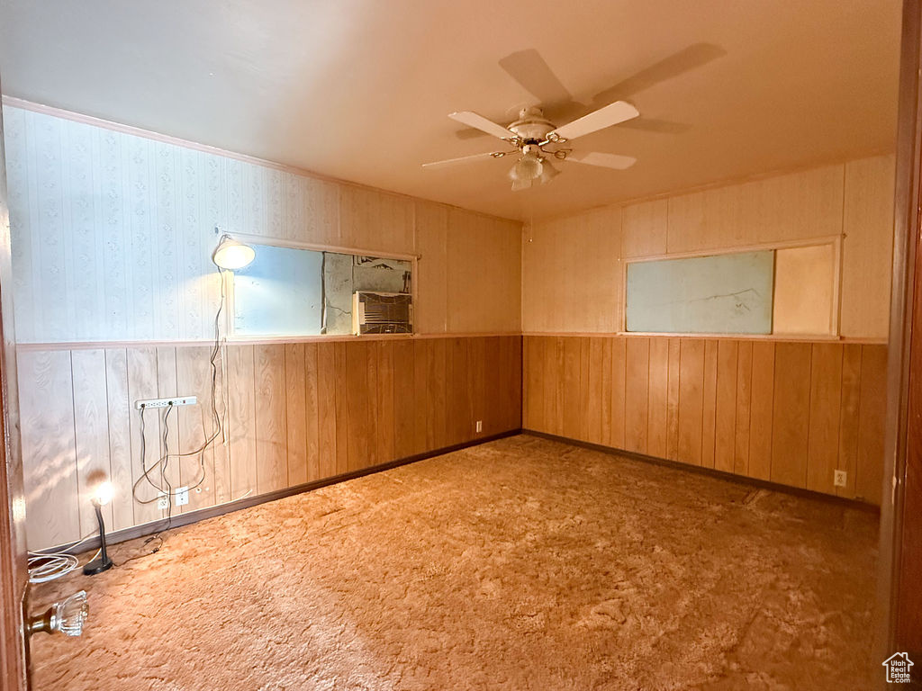 Empty room with ceiling fan, wooden walls, and a wainscoted wall