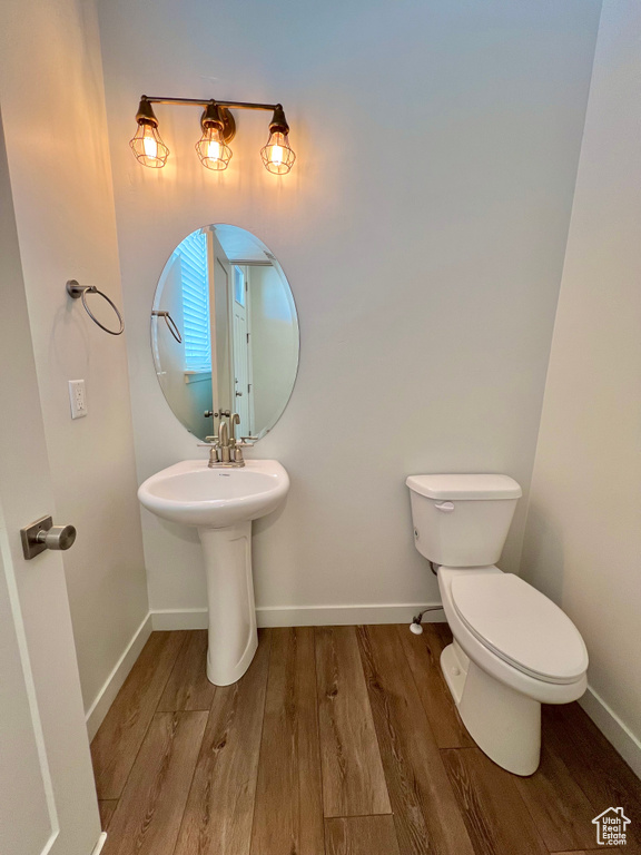 Bathroom with toilet, baseboards, and wood finished floors
