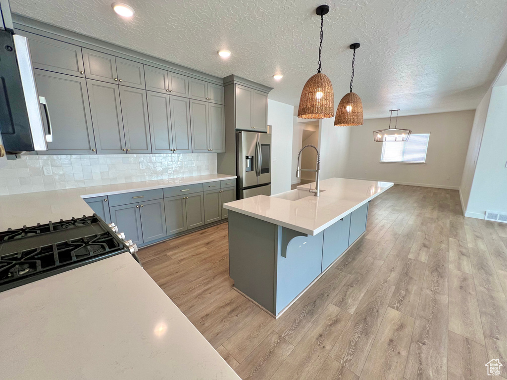 Kitchen with a sink, light wood-type flooring, light countertops, and appliances with stainless steel finishes