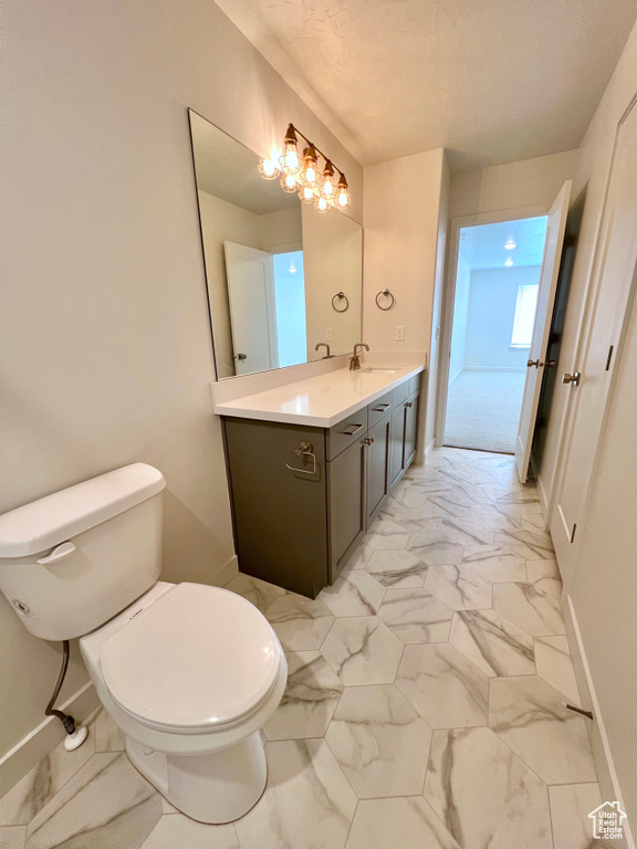 Bathroom featuring baseboards, marble finish floor, toilet, and vanity