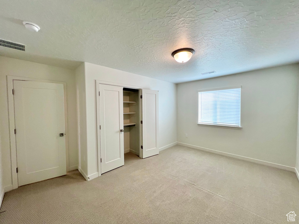 Unfurnished bedroom featuring baseboards, visible vents, and light carpet