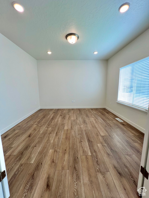 Spare room with recessed lighting, a textured ceiling, baseboards, and wood finished floors