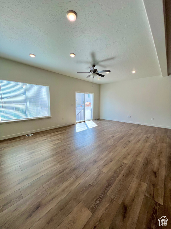 Empty room with baseboards, a textured ceiling, visible vents, and wood finished floors