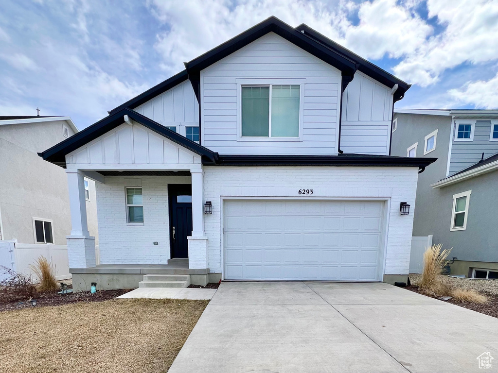 View of front of home featuring board and batten siding, driveway, and an attached garage