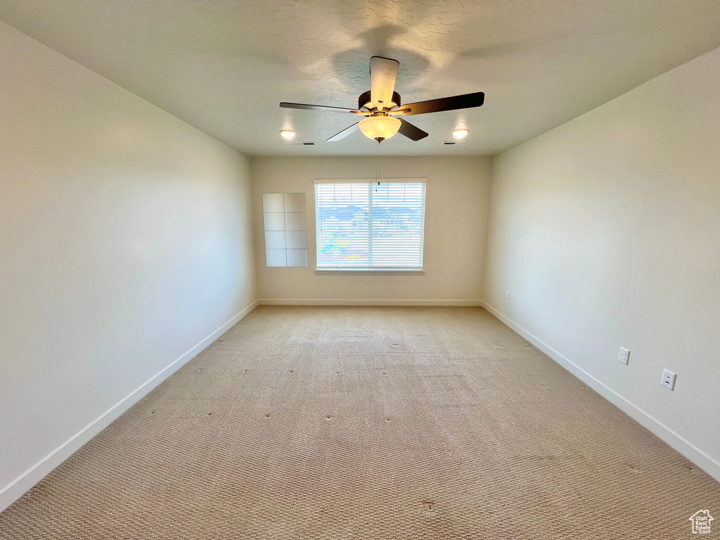 Unfurnished room featuring baseboards, a ceiling fan, and light colored carpet