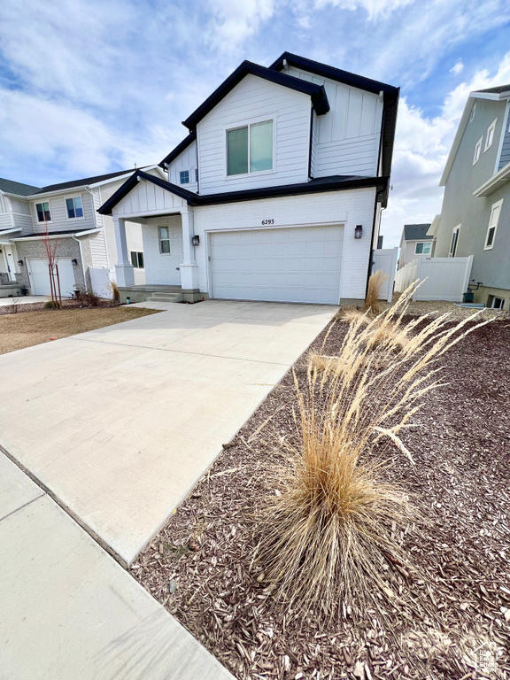 View of front of property with fence, an attached garage, board and batten siding, and concrete driveway