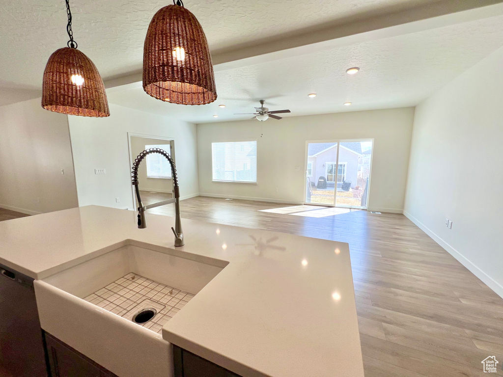 Kitchen featuring light countertops, a sink, light wood-style floors, and a textured ceiling