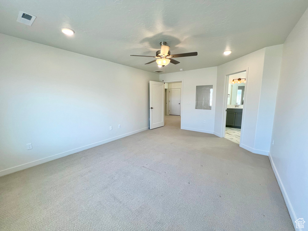 Unfurnished bedroom with light carpet, a textured ceiling, ensuite bathroom, baseboards, and visible vents