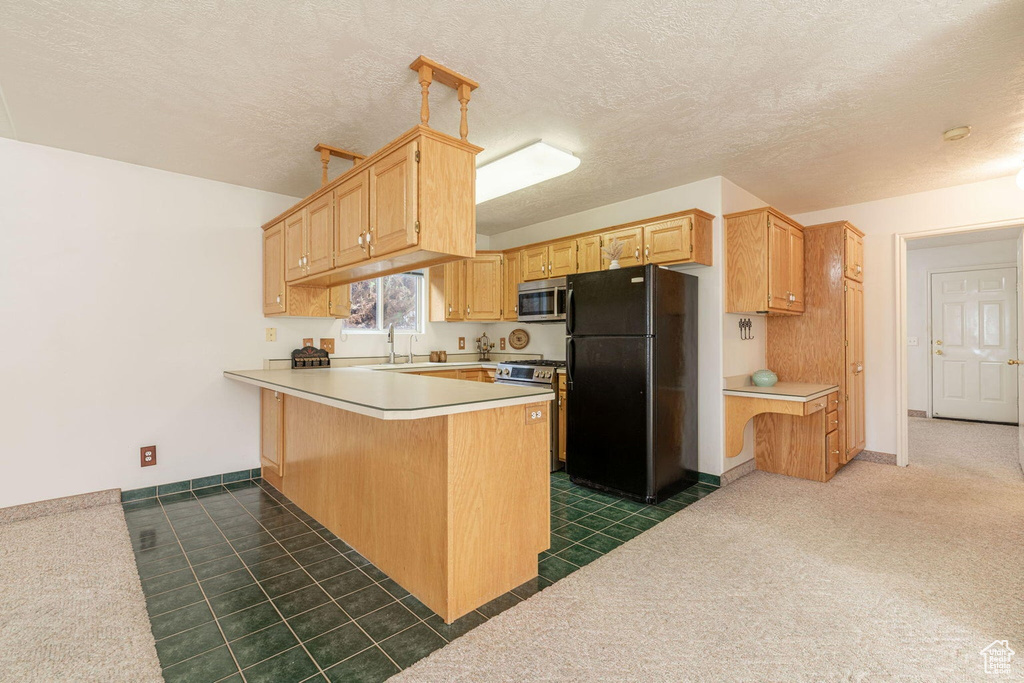 Kitchen with stainless steel appliances, a peninsula, light countertops, and a sink