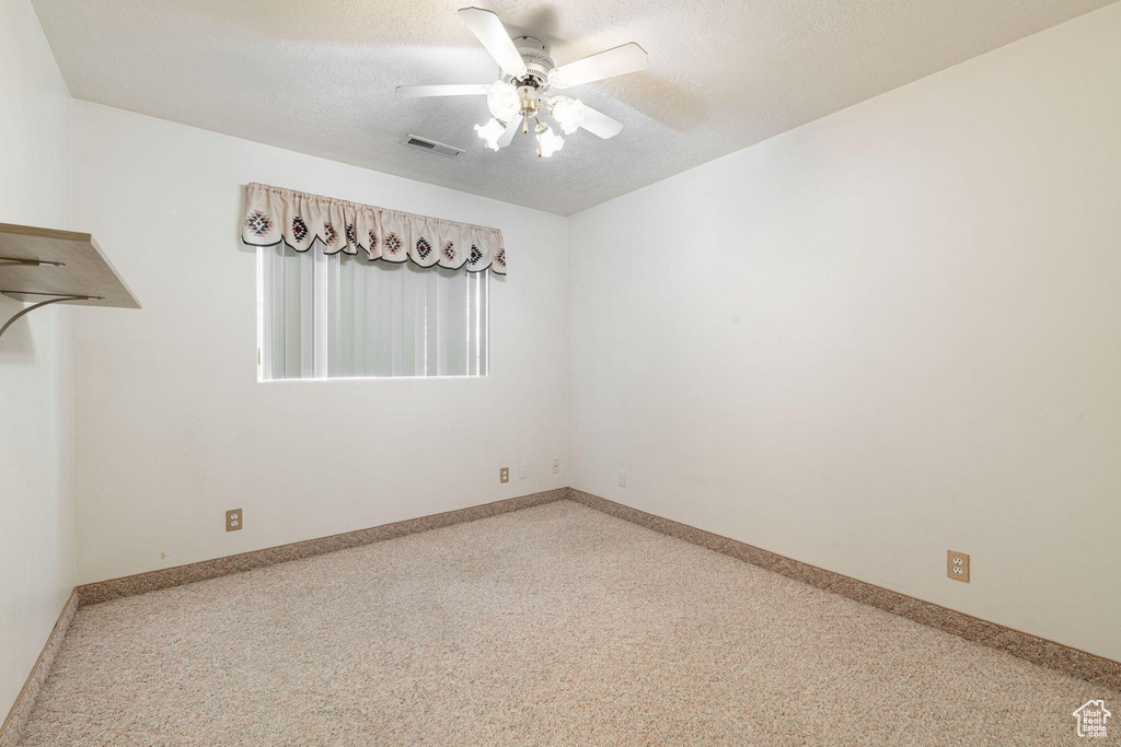 Unfurnished room featuring a textured ceiling, baseboards, a ceiling fan, and visible vents