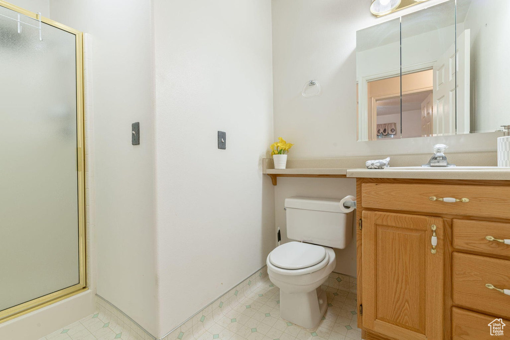 Bathroom featuring toilet, tile patterned floors, vanity, and a shower stall