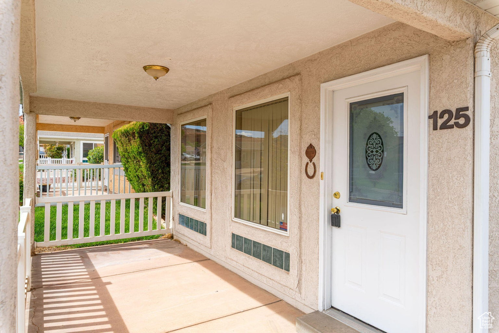 Doorway to property with a porch and stucco siding