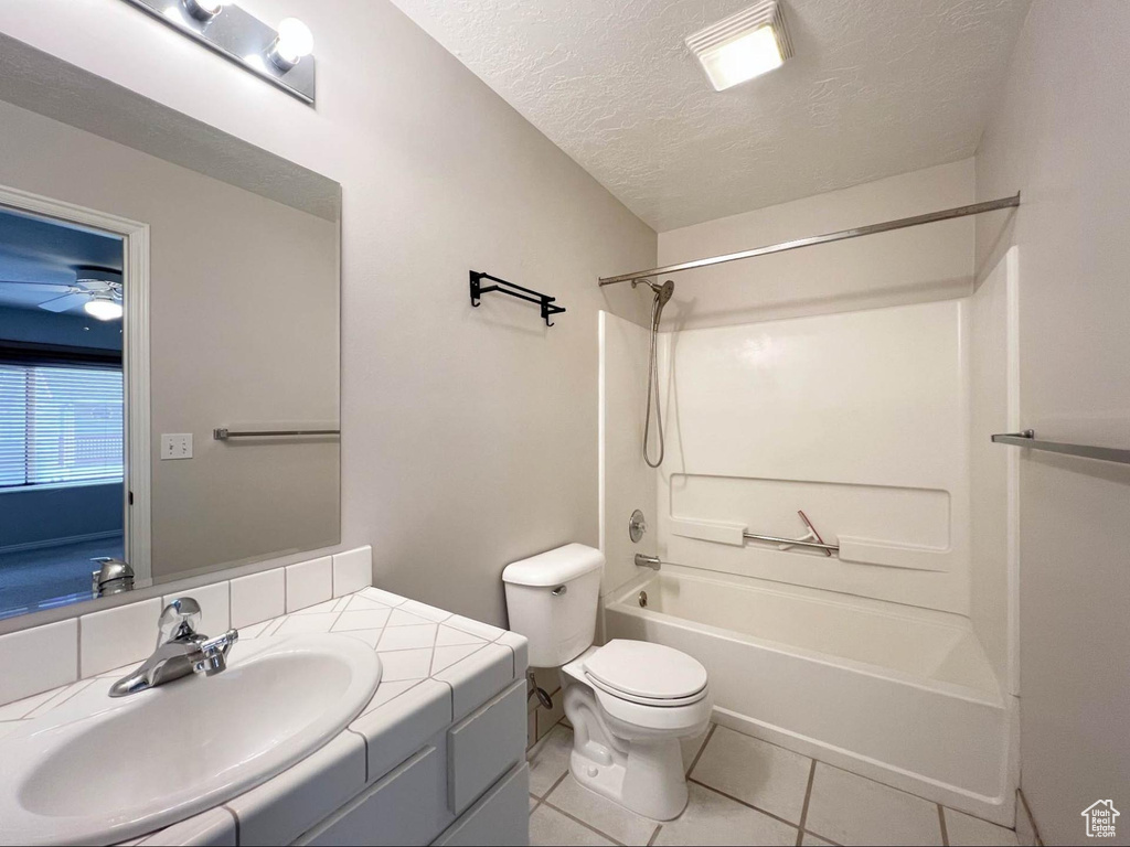 Bathroom featuring toilet,  shower combination, a textured ceiling, vanity, and tile patterned flooring