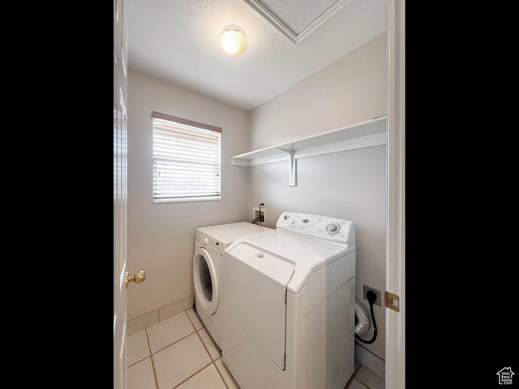Laundry room featuring laundry area, light tile patterned floors, washing machine and dryer, and a textured ceiling