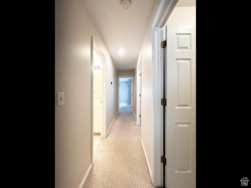 Corridor featuring light carpet and baseboards