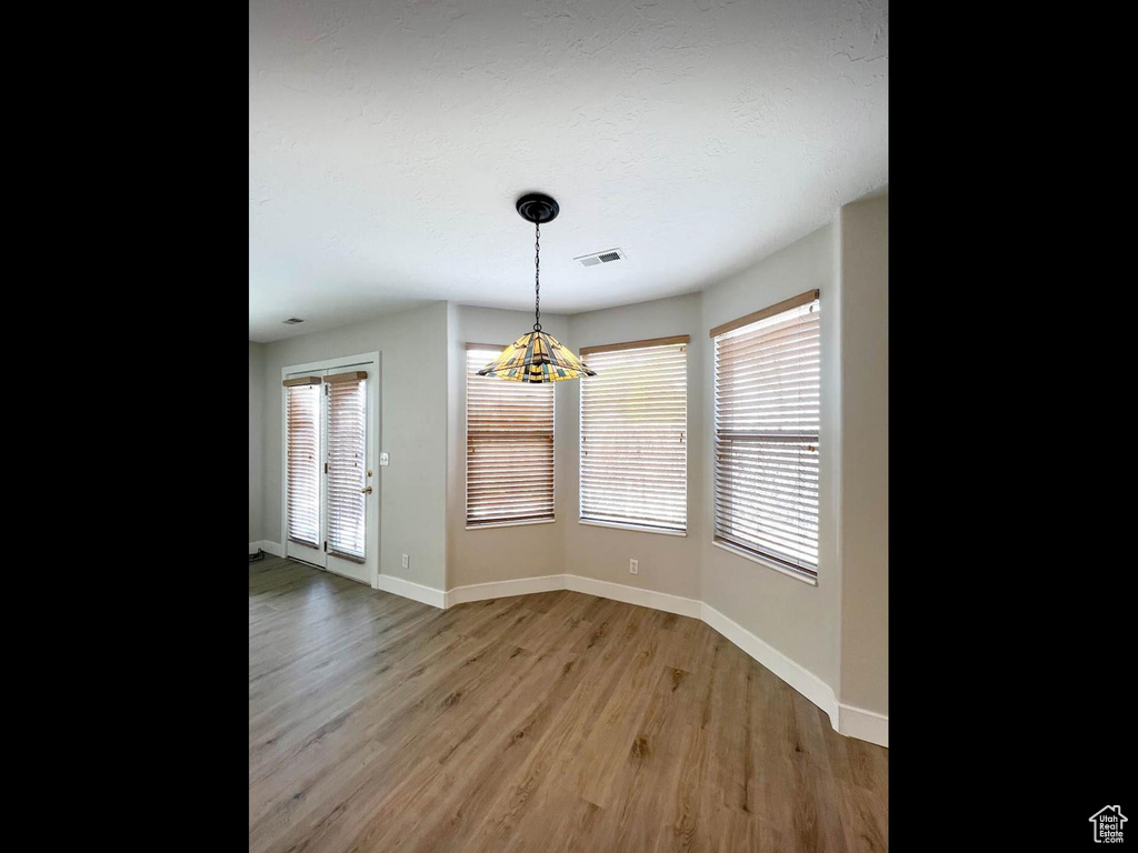 Unfurnished dining area with visible vents, baseboards, an inviting chandelier, and light wood-style floors