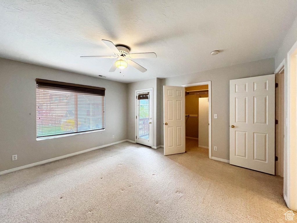 Unfurnished bedroom featuring access to outside, baseboards, light carpet, a textured ceiling, and ceiling fan